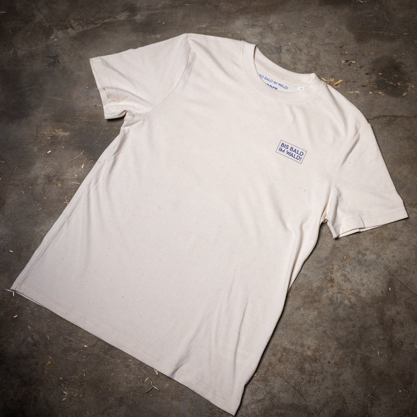 Die Vorderseite des Waldshirt Leberblümchen im Großformat. Auf der Brust links ist eine Box gedruckt, in der steht BIS BALD IM WALD! in Leberblümchen-Blau.